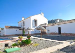 a white house with a pool and an umbrella at Cortijo Las Caballerias in Alora