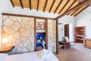 a bedroom with a bed with a stone wall at Cortijo Las Caballerias in Alora