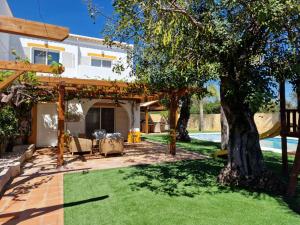 een achtertuin met een houten pergola en gras bij Real Village in Quarteira