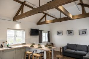 a kitchen and living room with a table and a couch at Exclusive Coach House with Lakeside Hot Tub on Country Estate in Toddington