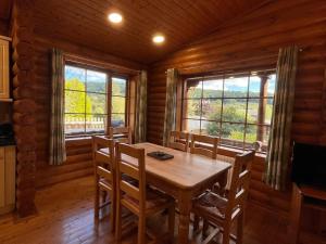 a dining room with a table and chairs and windows at Solid Log Cabin With Private Hot Tub - Oak in Aymestrey