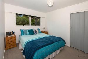 a bedroom with a bed and a window at Tui's Song Bach on the Bay in Whangarei