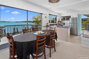 a kitchen and a dining room with a table and chairs at Tui's Song Bach on the Bay in Whangarei