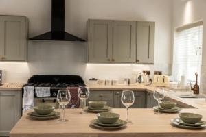 a kitchen with a table with wine glasses on it at Exclusive Coach House with Lakeside Hot Tub on Country Estate in Toddington