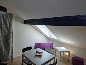 a living room with a table and a purple couch at L'Appartement et Le Studio in Chexbres