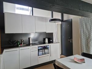 a kitchen with white cabinets and a table at L'Appartement et Le Studio in Chexbres