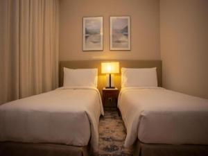 2 camas en una habitación de hotel con una lámpara entre ellas en Ocean View Address Beach Resort Fujairah فندق و منتجع شاطئ العنوان الفجيره, en Sharm