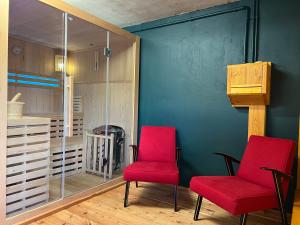 2 chaises rouges assises à côté d'un mur bleu dans l'établissement Houten Vakantiewoning "ReisnaarPolen" inclusief royaal ontbijt, sauna en gids, à Czarna Góra