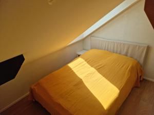 a bedroom with a yellow bed in a attic at L'Appartement et Le Studio in Chexbres