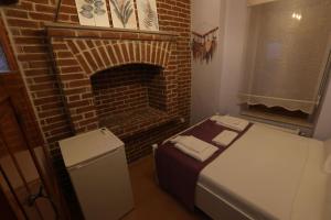 um pequeno quarto com uma lareira de tijolos e uma cama em Cunda Pera Otel em Ayvalik