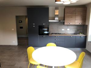 a kitchen with a white table and yellow chairs at 50 SFUMATURE DI SUITE in Genova