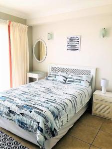 a bedroom with a bed with a blue and white comforter at Aquarella 1 in Plettenberg Bay