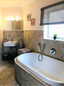 a bathroom with a large tub and a sink at Aquarella 1 in Plettenberg Bay