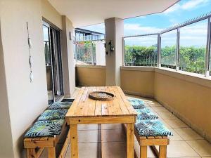 a wooden table and bench on a balcony with windows at Aquarella 1 in Plettenberg Bay