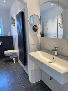 a bathroom with a sink and a toilet and a mirror at Austernfischer - Haus 12 in Lenste +14 photos