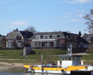 un bateau jaune sur l'eau devant une maison dans l'établissement Aan Het Veer minimaal 4 overnachtingen, à Dieren