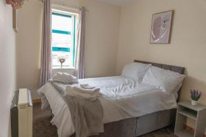 a bedroom with a bed with white sheets and a window at City Centre Riverview Apartment in Derry Londonderry