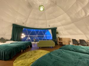 Tomamuにあるグランピングステイトマムのベッド3台、窓が備わるテントの客室です。