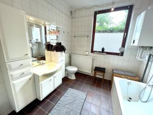uma casa de banho com um lavatório, um WC e uma janela. em Fischerhuus em Eckernförde
