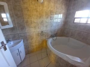 a bathroom with a tub and a toilet and a sink at DEN VIEW GUESTHOUSE in Francistown