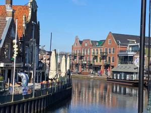 un río con barcos atracados en una ciudad con edificios en BENNO » Segelyacht am Ijsselmeer mit 3 Kabinen, en Lemmer