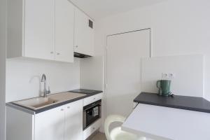 a white kitchen with white cabinets and a sink at Studio Cosy 2 min Gare - 10 min in Bussy-Saint-Georges
