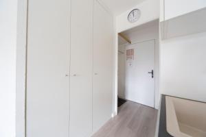 a hallway with white cabinets and a clock on the wall at Studio Cosy 2 min Gare - 10 min in Bussy-Saint-Georges