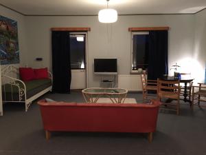 Vitaby Järnvägshotell في Vitaby: غرفة معيشة مع أريكة حمراء وطاولة