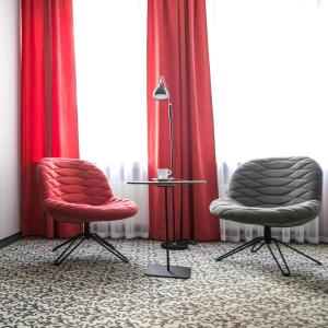 dwa krzesła i lampa w pokoju z czerwonymi zasłonami w obiekcie No.23 Premium Aparthotel w Krakowie