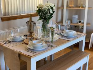 a table with plates and glasses and a vase of flowers at Lomond View in Luss