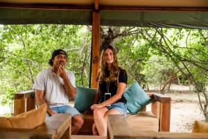 Ein Mann und eine Frau sitzen auf einer Veranda in der Unterkunft Wild Trails Yala by Suri in Yala