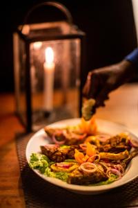 a plate of food on a table with a candle at Wild Trails Yala by Suri in Yala
