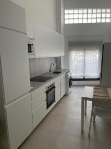 eine Küche mit weißen Schränken, einem Tisch und einem Waschbecken in der Unterkunft MN Homes Fonseca B in Málaga