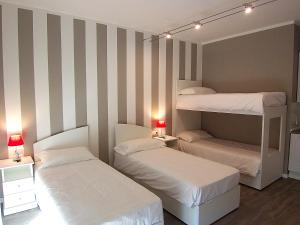 two beds in a room with striped walls at B&B Vinago Belvedere in Mornago