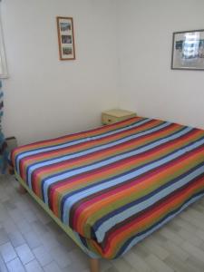 łóżko z kolorowym kocem w paski w obiekcie 5097 Tennis Village 1603 w Cap d'Agde