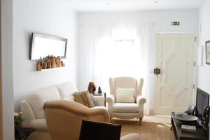 a living room with white furniture and a window at Casa dos Clérigos in Alcácer do Sal