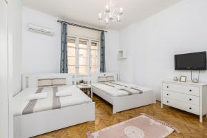 a white bedroom with two beds and a tv at Real Apartments Wesselényi II. in Budapest