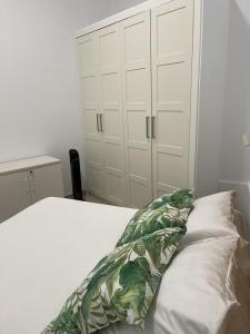 ein weißes Bett mit einem grünen und weißen Kissen in der Unterkunft MN Homes Fonseca B in Málaga