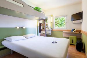 a large white bed in a room with a window at ibis budget Poitiers Nord Futuroscope in Chasseneuil-du-Poitou