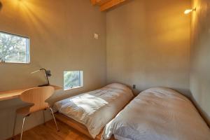 two beds in a room with a desk and window at YHouse in Kumamoto