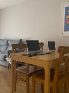 dwa laptopy ustawione na drewnianym stole w salonie w obiekcie El Cierrón - apartamento con terrazas! w mieście Villaviciosa