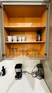 um balcão de cozinha com tigelas e copos nas prateleiras em Brand New Spacious 2br - 2bth Basement em Woodbridge