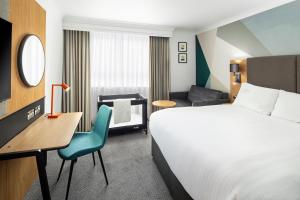 ベクスリーにあるホリデイ イン ロンドン ベクスレーのベッド、デスク、椅子が備わるホテルルームです。