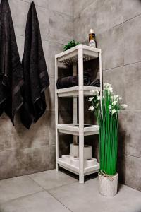 a white shelf in a bathroom with a vase of flowers at Lavender Hill Apartment in Gdańsk