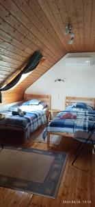 dwa łóżka w pokoju z drewnianym sufitem w obiekcie Marika apartman w mieście Balatongyörök