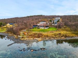 un grupo de casas en una colina junto a un cuerpo de agua en Hus med egen strandlinje, en Tromsø