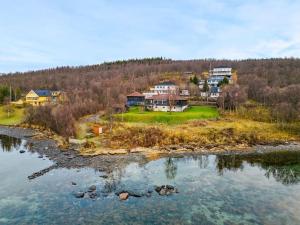 a group of houses on a hill next to a body of water at Hus med egen strandlinje in Tromsø