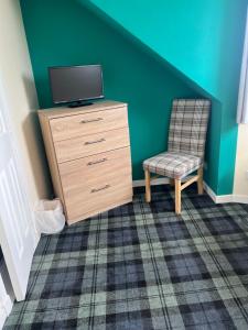 a room with a dresser and a tv and a chair at Budget Rooms in Inverness