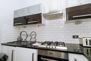 uma cozinha com um fogão e uma parede de azulejos brancos em Beautiful Home In Stockbridge Edinburgh em Edimburgo