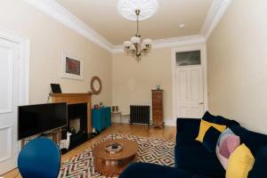 a living room with a blue couch and a tv at Beautiful Home In Stockbridge Edinburgh in Edinburgh